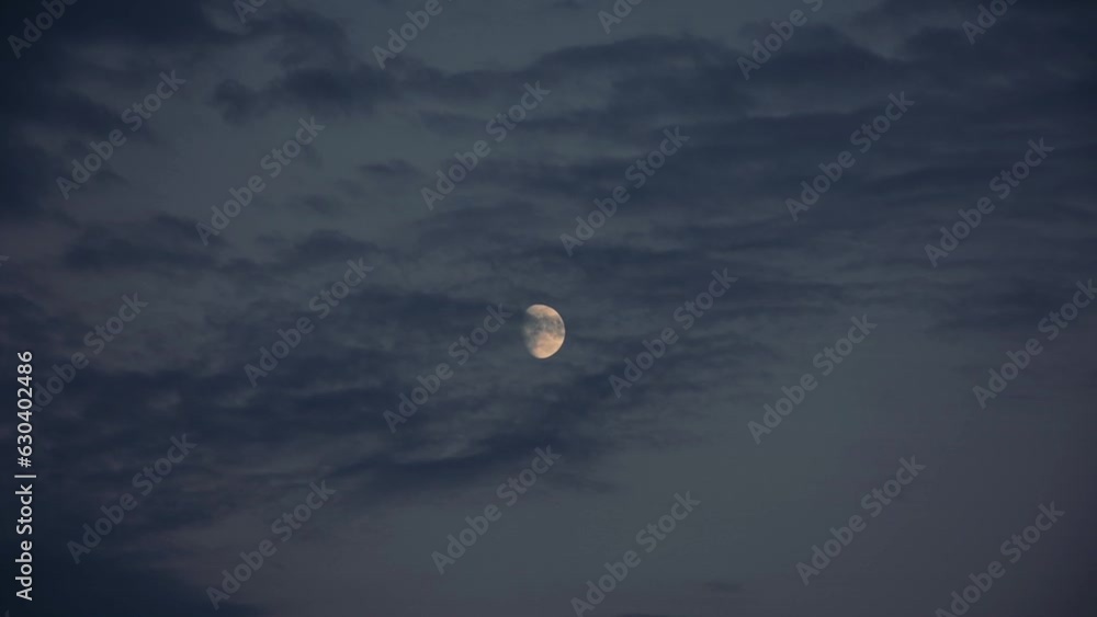 Moon moving through gray cloudy sky in the evening Moon moving through gray cloudy sky in the evening