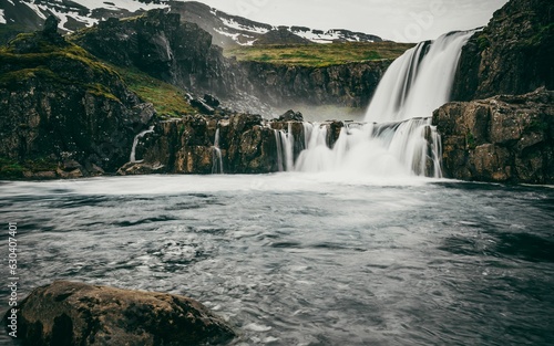 Majestic waterfall cascading from a lush valley near the mountains in Seydisfjordur, Iceland