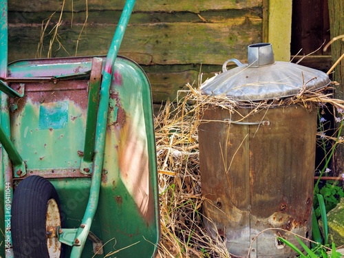 Fotografija Old wheel barrow and fire bin in the garden
