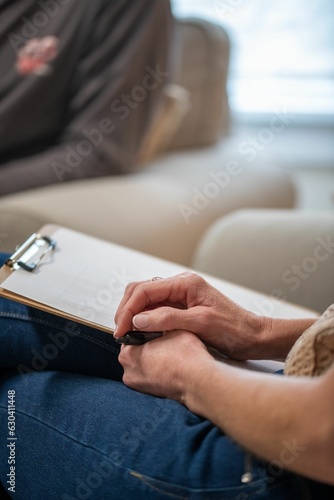 People in a professional therapy session, the therapist taking notes as the client talks