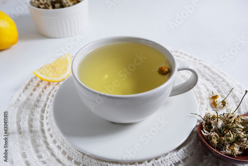 A decoction of chamomile brewed in a white cup on a white napkin on a light background. Medicinal decoction of chamomile, herbal tea.