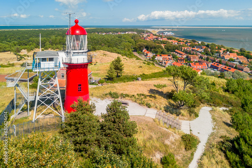 Aerial drone image of Vlieland. With bright red Lighthouse on top of a dune overlooking the small town, the North Sea and the Wadden Sea photo