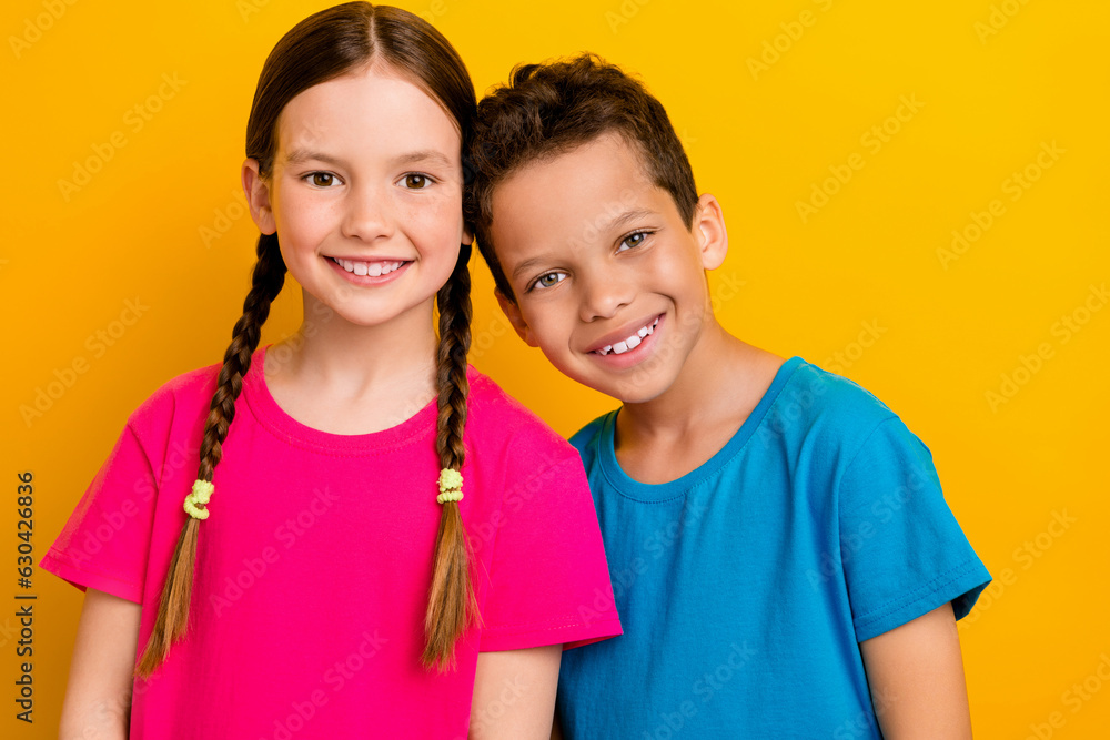 Photo of funky positive preteen schoolkids dressed t-shirts embracing empty space isolated yellow color background Photo of funky positive preteen schoolkids dressed t-shirts embracing empty space isolated yellow color background