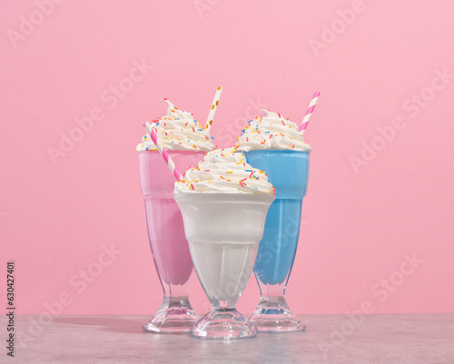 Delicious whipped cream milkshakes in glasses with colored sprinkles and colorful straws. Party and festive vacation.