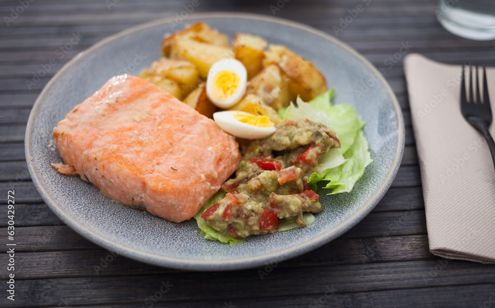 Salmon fillet with fried potato slices, homemade guacamole and quail egg halves Salmon fillet with fried potato slices, homemade guacamole and quail egg halves