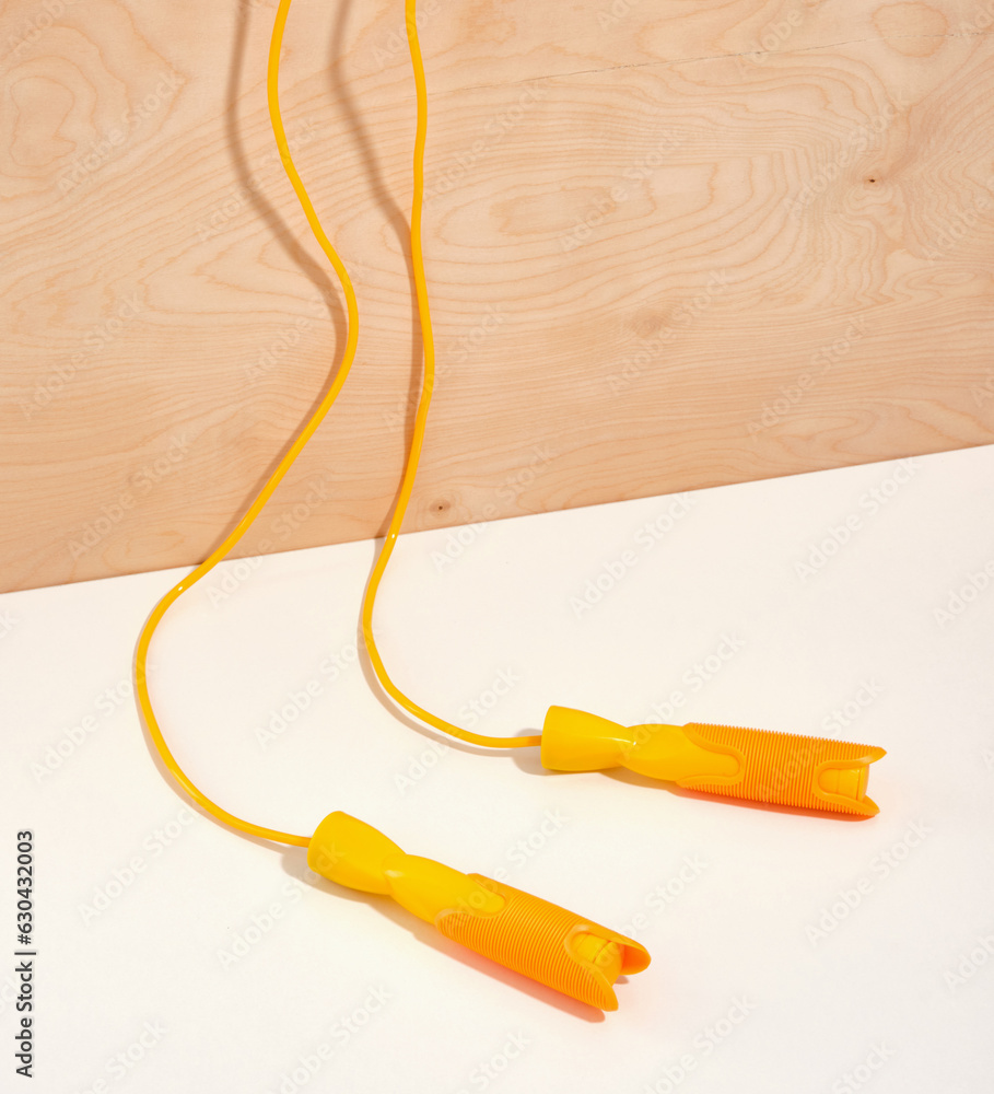 A bright yellow long jump rope for exercise and weight loss. Exercise in a gym or at home. A bright yellow long jump rope for exercise and weight loss. Exercise in a gym or at home.
