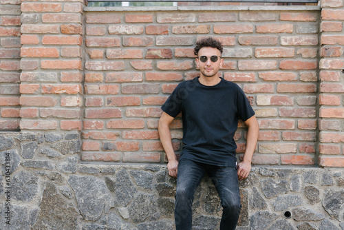 Hipster handsome male model wearing black blank t-shirt with space for your logo or design in casual urban style