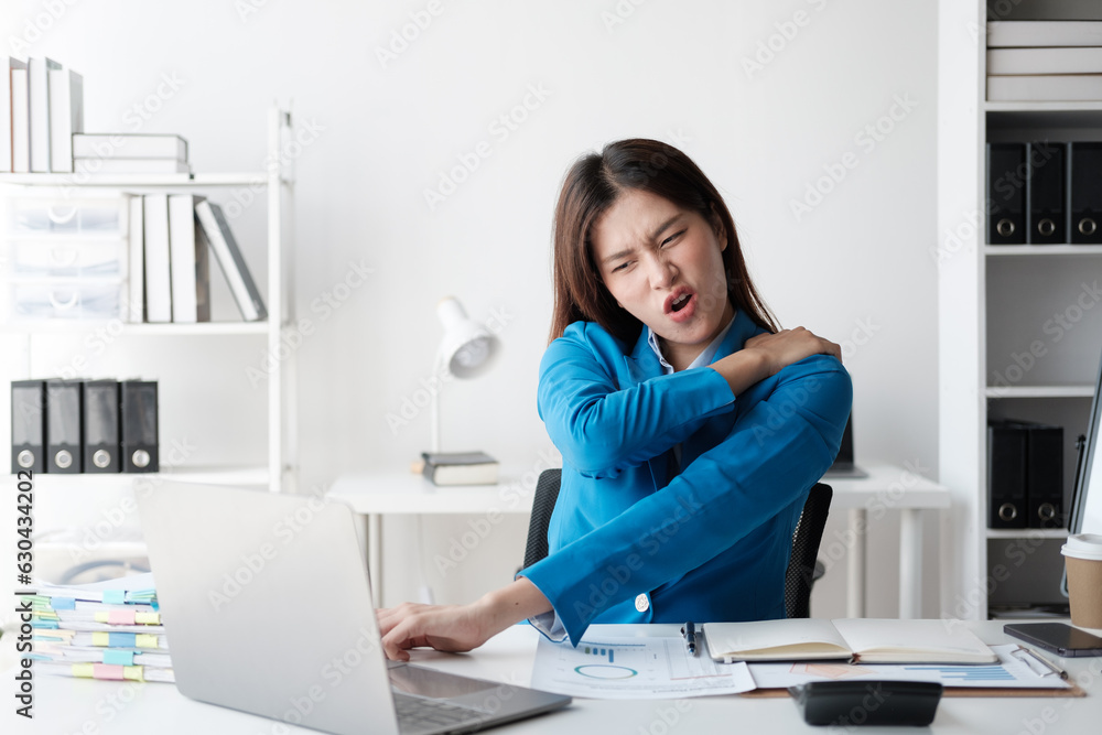 Businesswoman suffering shoulder pain sitting in a chair while working with a desktop computer. Businesswoman suffering shoulder pain sitting in a chair while working with a desktop computer.