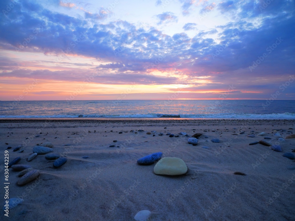 Obraz premium Sonnenuntergang an steinigem Strand