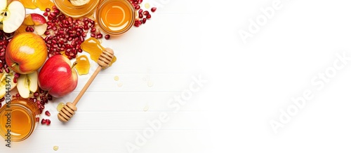 Rosh Hashanah, the Jewish New Year holiday, is depicted with a creative layout of traditional symbols such as apples, honey, and pomegranate. The layout is isolated on a white background, captured photo