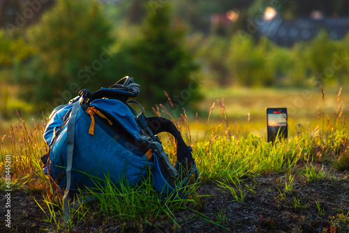 Color evening meadow near Bozi Dar village with sunset mobile phone and backpack photo