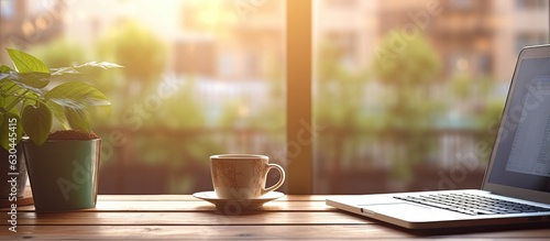 The Home Office Concept portrays a designated area for working from home, situated near a window. It features a modern laptop with a blurred screen and a glass cup of tea on the table. is a close-up