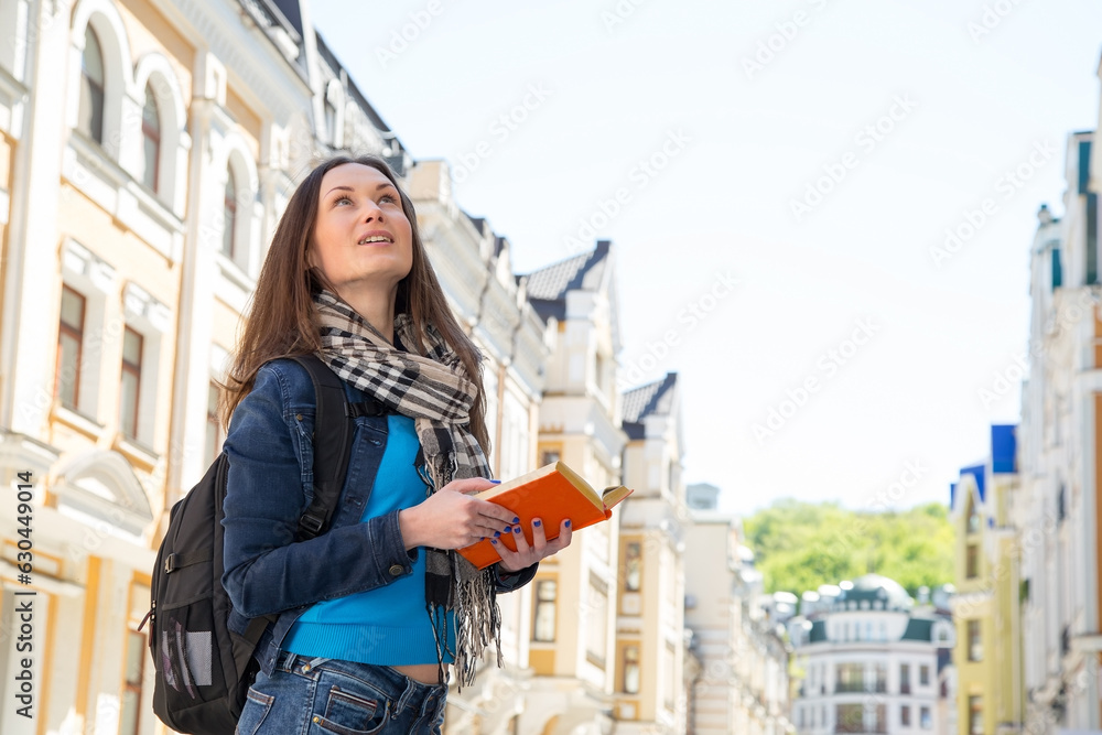 Young woman traveler with a backpack on her shoulder. Independent travel and out sightseeing in a history city. Student woman, her vacation. Learning foreign languages in a different country. Travel.