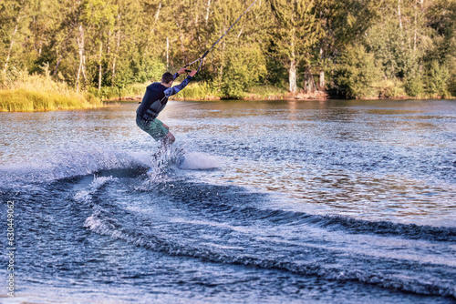 Wakeboarding on the sea on summer day in life jacket. Soft focus. Action blur.