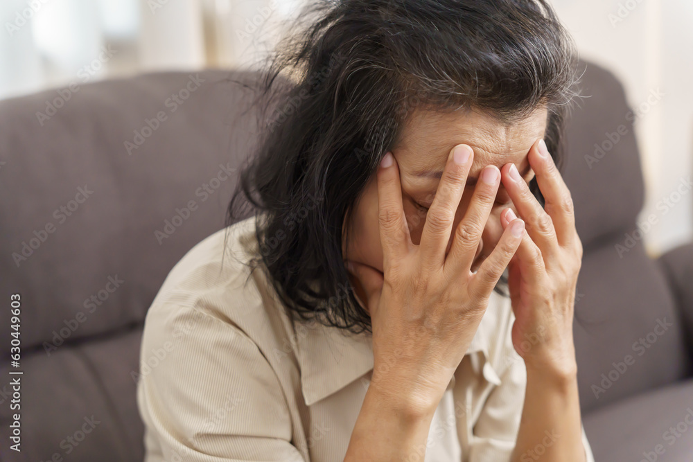 Sad middle age Asian woman touching forehead having headache suffering from migraine. mature asian woman feeling sick or depression. Sad middle age Asian woman touching forehead having headache suffering from migraine. mature asian woman feeling sick or depression.