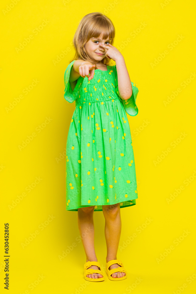I am watching you. Young blonde school girl pointing at her eyes and camera, show I am watching you gesture, spying on someone. Preteen female child kid isolated on studio yellow background. Vertical I am watching you. Young blonde school girl pointing at her eyes and camera, show I am watching you gesture, spying on someone. Preteen female child kid isolated on studio yellow background. Vertical
