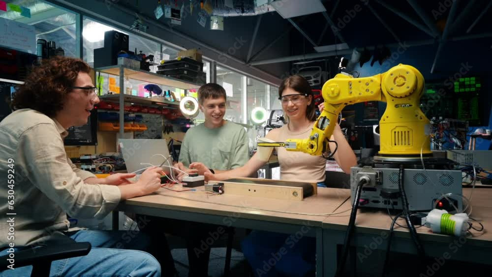 Group of young people doing experiments in robotics in a laboratory. Robots and tools on the table Group of young people doing experiments in robotics in a laboratory. Robots and tools on the table