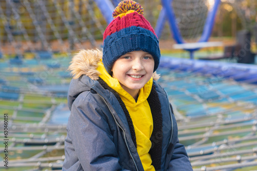 happy boy playing on rope complex, playground in autumn park.portrait of a happy boy, child, schoolboy in a hat and jacket, in autumn on the playground photo