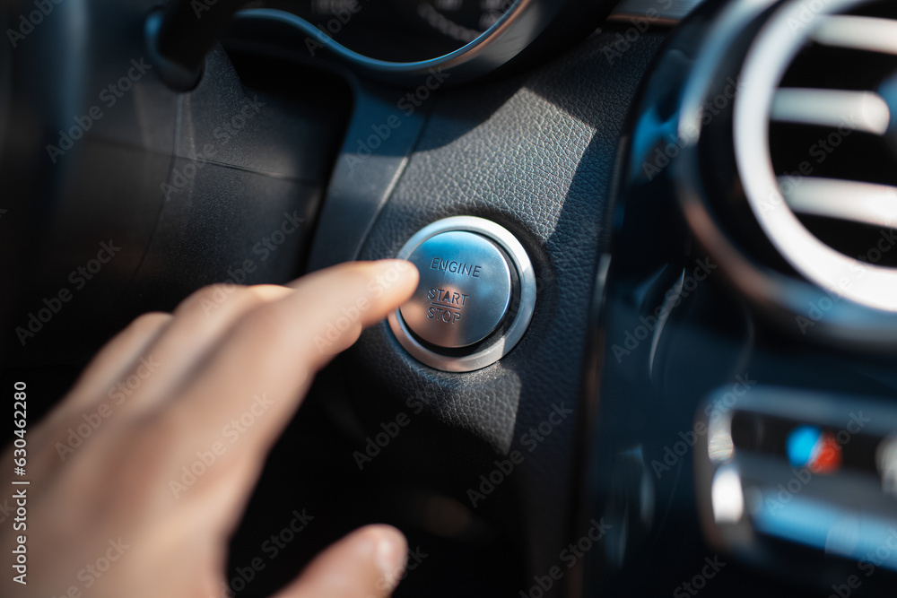 A male finger press the car button of engine start stop.
