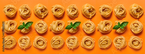 Many dry pasta nests with basil on orange background, top view