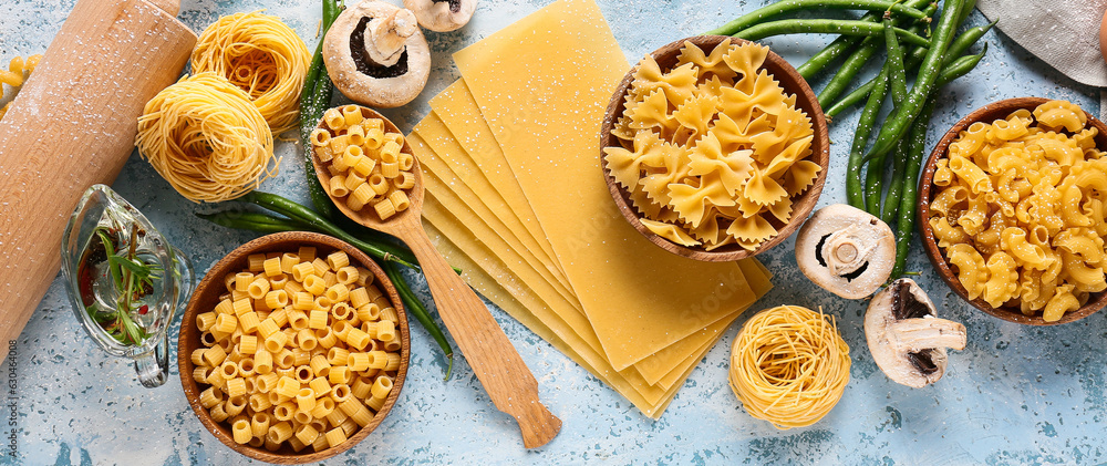 Assortment of different types of pasta, mushrooms and green beans on light blue background