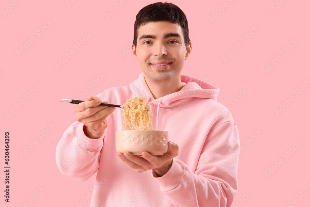Young man with bowl of Chinese noodles on pink background Young man with bowl of Chinese noodles on pink background
