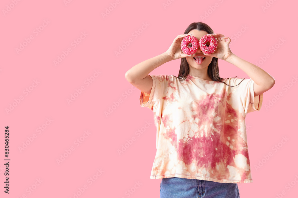 Funny young woman in tie-dye t-shirt and with donuts on pink background Funny young woman in tie-dye t-shirt and with donuts on pink background