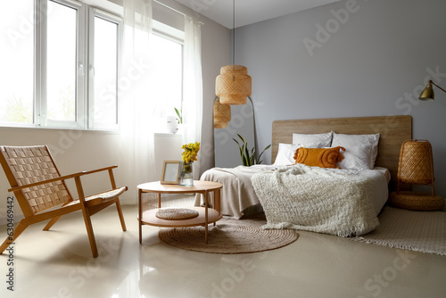 Interior of light bedroom with armchair  table and mirror