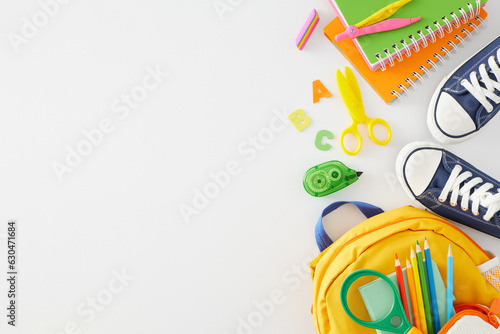 Back-to-school concept. Top view flat lay of blue shoes, assorted school materials, schoolbag, colorful letters on white background with empty space for promo or text