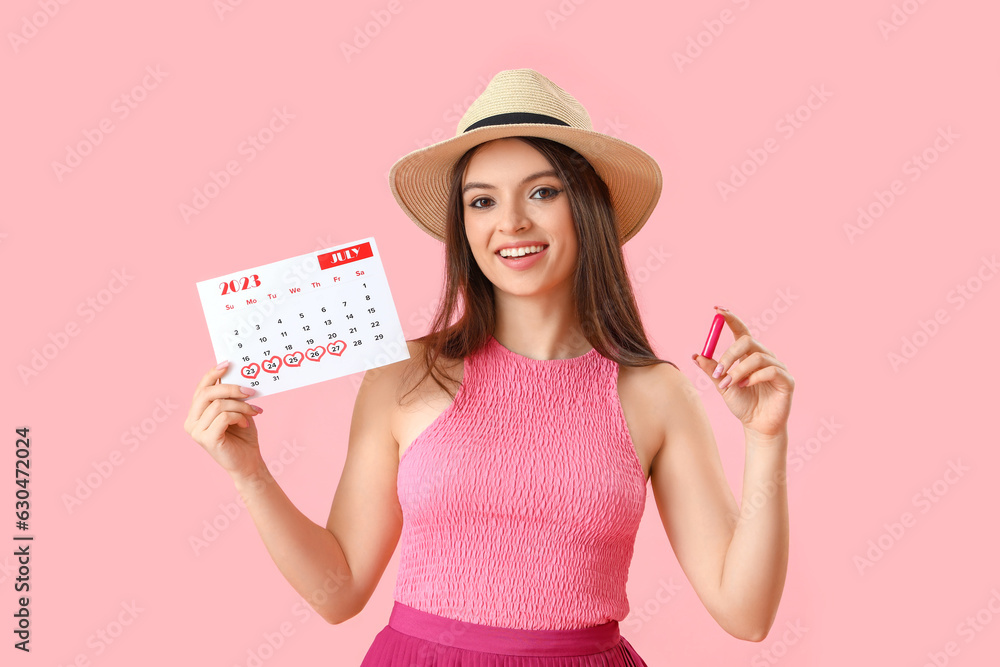 Young woman with menstrual calendar and tampon on pink background Young woman with menstrual calendar and tampon on pink background