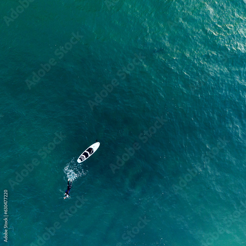 Imagen aérea de un nadador y tabla de surf en el mar de Rosarito, México photo