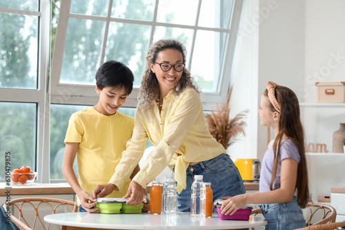Mother with her little children packing school lunch in kitchen