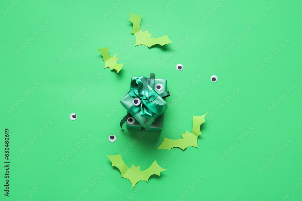 Obraz premium Green halloween gift boxes with googly eyes and paper bats on a bright green background, spooky holiday celebration, this festive composition represents a spooky holiday celebration and october party