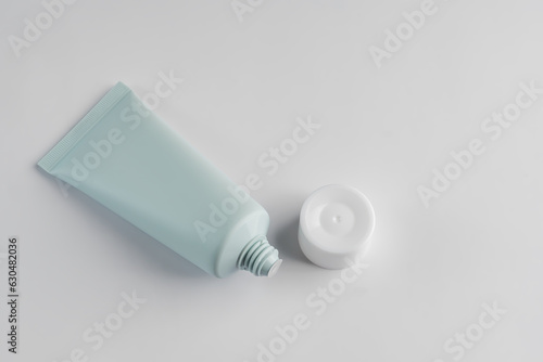 Top view of green squezze tube with open cap on white background. Cosmetics mockup.