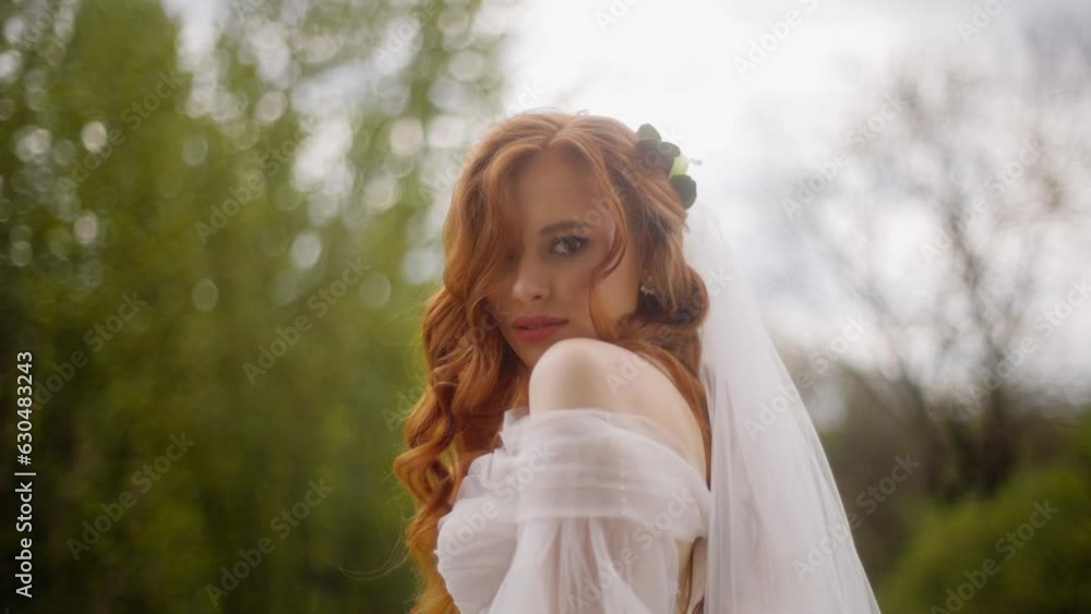 Portrait of a beautiful luxury fashion bride with red hair flowing in the wind. Attractive woman in a wedding dress with a veil gazes looking enchantingly into the camera. Portrait of a beautiful luxury fashion bride with red hair flowing in the wind. Attractive woman in a wedding dress with a veil gazes looking enchantingly into the camera.
