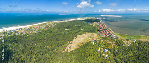 Aerial drone image of the island Vlieland. With bright red lighthouse on top of a sand dune overlooking the small town, Terschelling, the North Sea and the Wadden Sea. Blue sky, summer and red roofs photo