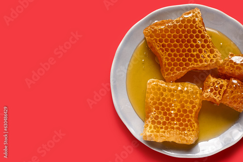 Plate with sweet honeycombs on red background