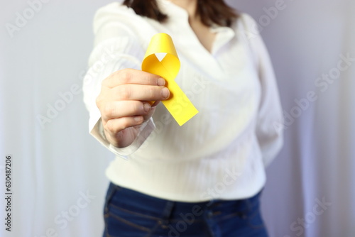 Woman wearing casual clothes holding in the hands a yellow ribbon. 