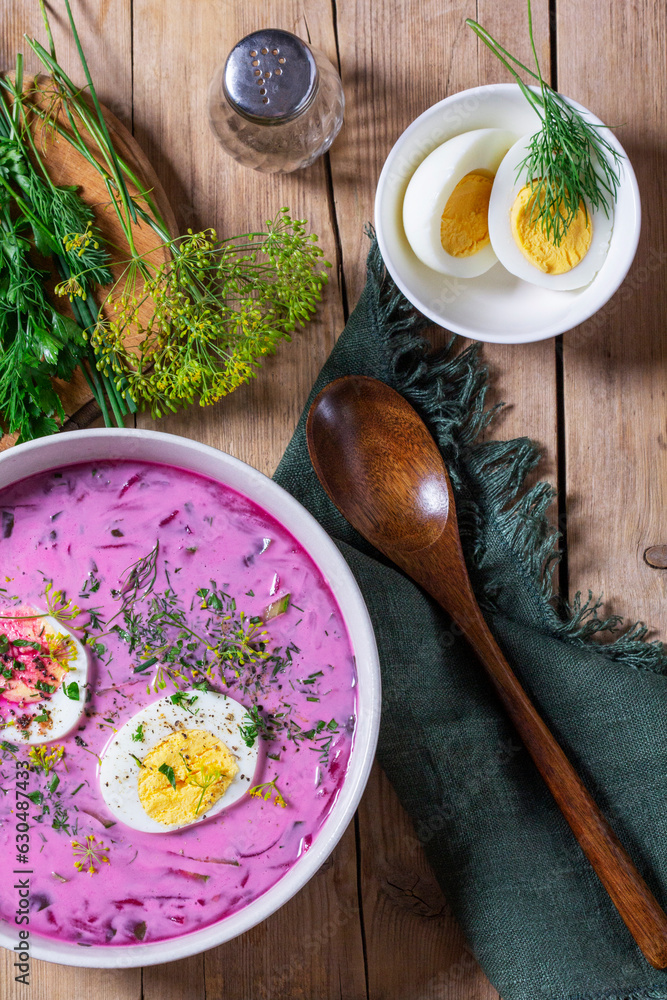 Traditional summer cold beetroot soup with cucumber, egg and sour cream on a wooden background. Rustic style.