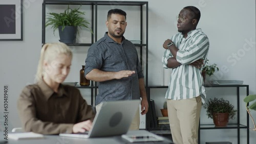 African American and Middle Eastern men standing behind their female co-worker slandering her on purposeAfrican American and Middle Eastern men standing behind their female co-worker slandering her on