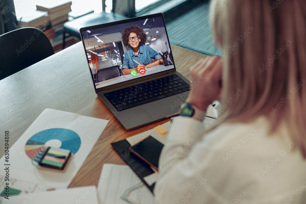 Woman analyst working with documents during video conference while sitting in modern coworking Woman analyst working with documents during video conference while sitting in modern coworking
