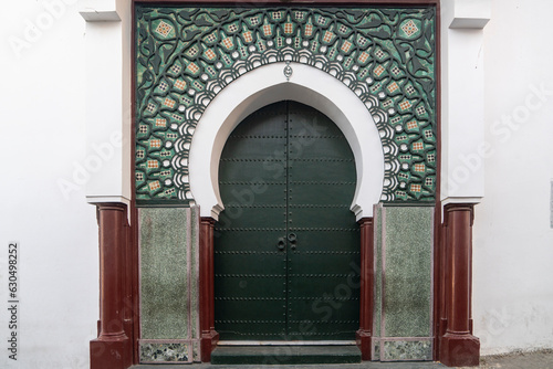 An ornamented gate in moorish style with geometric islamic patterns and  house painted white at Ksbah, Ancient Medina, Tangier, Morocco