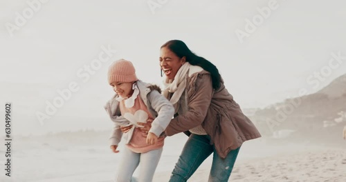 Playing, hug and a mother and child at the beach for a holiday, love or running together. Happy, playful and a young mom ahd a girl kid at the ocean in winter for bonding, care and a vacation photo
