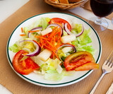 Healthy vegetable salad with fresh tomatoes, carrot, iceberg salad, sliced onion and olive oil