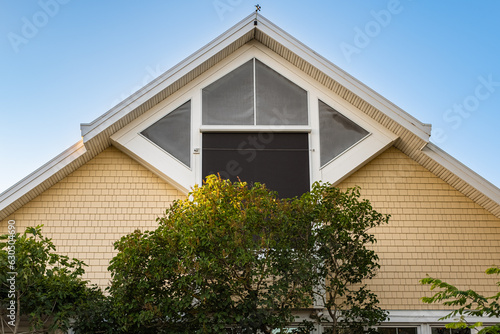 Top of the triangular roof of the house against the sky. Exterior Front House Facade. Top of the house with windows