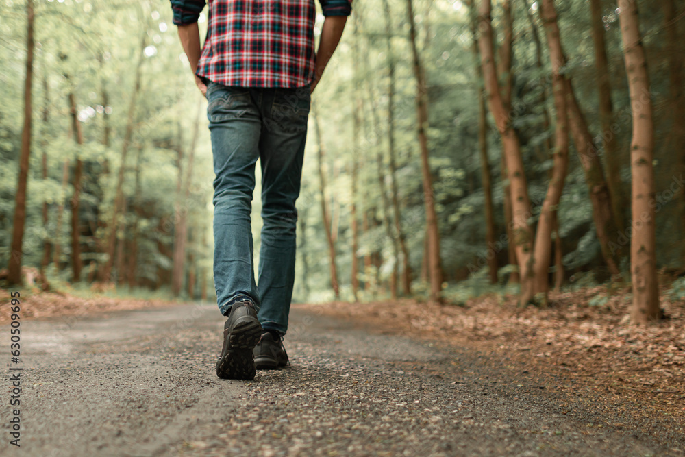 Man walking on sunlit trail in autumn forest enjoying peaceful walk in nature Man walking on sunlit trail in autumn forest enjoying peaceful walk in nature