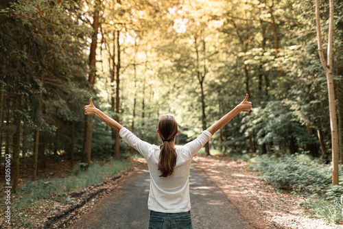Young woman in autumn forest raising arms, expressing carefree happiness and connection with nature.