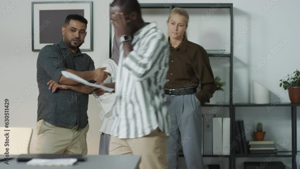 Group of three multi-ethnic managers standing in office staring at their Black colleague walking by mocking him Group of three multi-ethnic managers standing in office staring at their Black colleague walking by mocking him