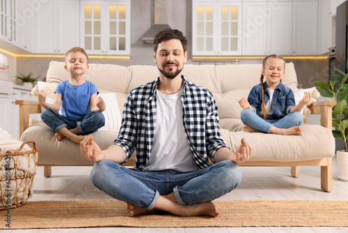 Father with children meditating together at home. Harmony and zen