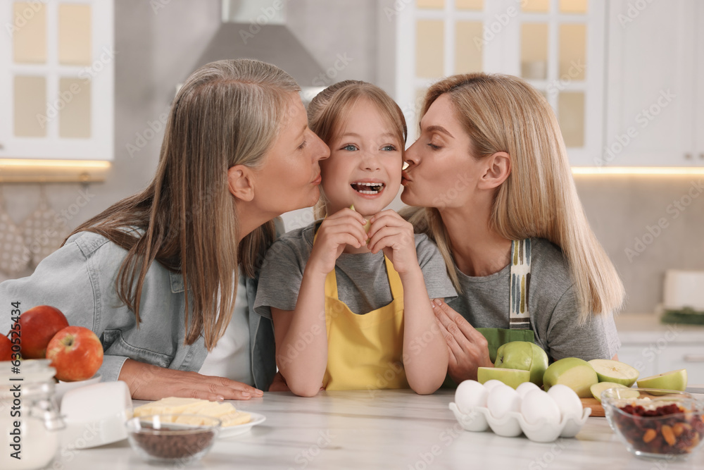 Three generations. Grandmother, her daughter and granddaughter in kitchen Three generations. Grandmother, her daughter and granddaughter in kitchen